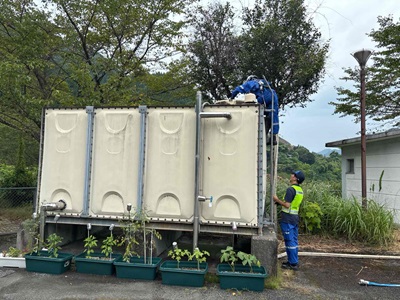 給水車からタンクに水を入れている作業員