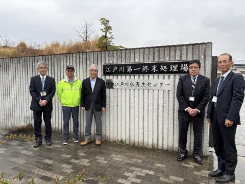 江戸川第一終末処理場の入り口前に立つ検討委員（屋外で撮影）