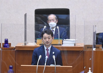 2月定例県議会招集日の様子。議長席の佐野議長と、登壇し挨拶を述べる熊谷知事