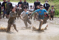 子どもたりがどろどろの田んぼの中を走っている写真