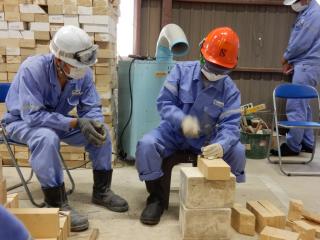 校外学習の様子。作業着、ゴーグル、ヘルメットを着用した生徒が木材を加工している。