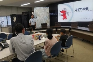 座って仕事内容の説明を受ける職員と職員の子どもの写真