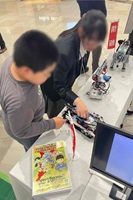 プログラミングを体験する来場者と、サポートする生徒の写真