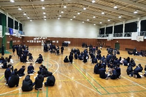 体育館で生徒たちがグループに分かれて座り話し合いをしている写真