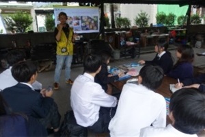 ホワイトボードの前で説明をする講師と説明を聞く教員・生徒の写真