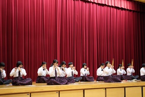 生徒たちが舞台に座り雅楽を披露している写真
