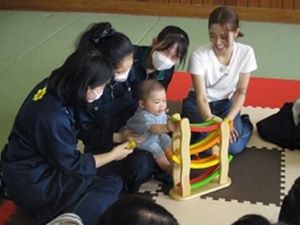 赤ちゃんと生徒が遊んでいる写真