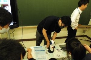 小学生がAIロボットに話しかけている写真