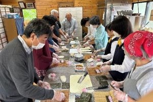 高校生も参加者と一緒に太巻き寿司作りをしている写真