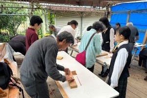 高校生が箸づくり体験の手助けをしている写真