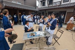 生徒が講師になって体験者に演奏を教えている写真