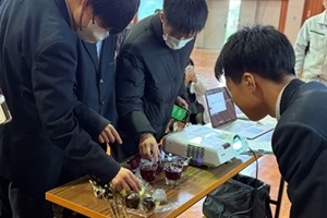 ボタニカルクラフトを触りながら説明をする3年生と、それをのぞき込む後輩の写真