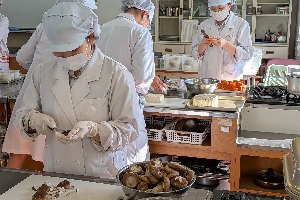 生徒たちが調理室で松花堂弁当の材料を切っている写真