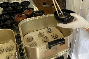 生徒が椀物の具をお椀に盛り付けている写真