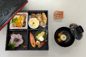 完成した松花堂弁当と汁物の写真。弁当箱の左上にすき焼き、右上に天ぷらとグラタン、右下に前菜とデザート、左下にご飯が入っている。