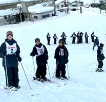 列を作り、雪の斜面を登る生徒たちの写真