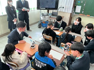 高校生が小学生にロボットについて説明している写真