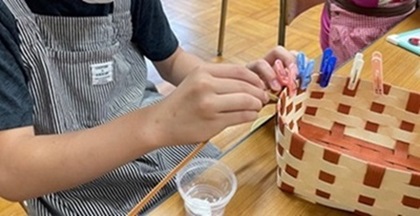 生徒が小物入れのクラフトテープを編んでいる様子