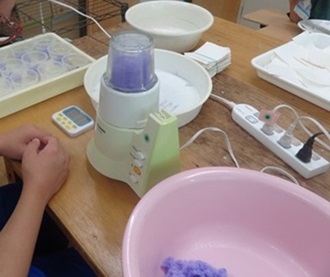 生徒が油吸い取り用の綿をミキサーにかけている様子