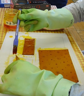 生徒がレザーのペンケースにはけで染色している様子