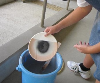 生徒が陶器に釉薬をかけている様子