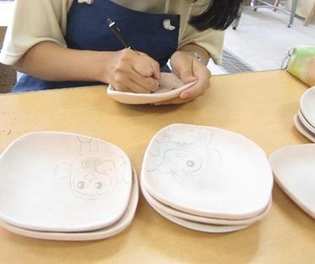 生徒が陶器に絵を描いている様子