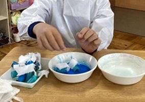 生徒が青い染料で布を染めている様子