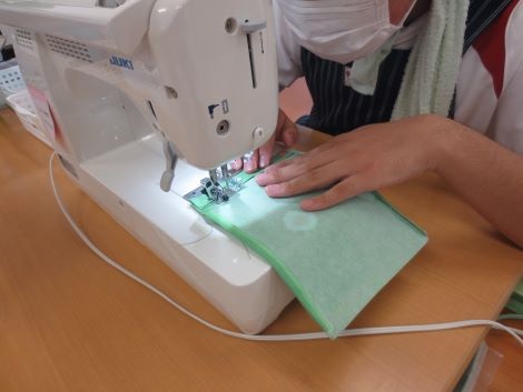 生徒がミシンで巾着の布を縫っている様子