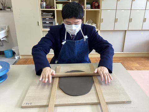 生徒が丸小皿の材料を棒で伸ばしている写真
