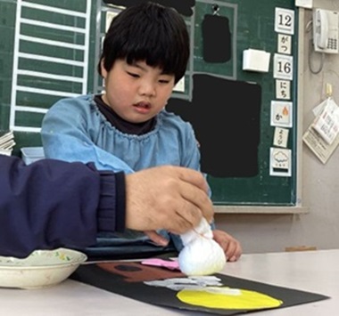 生徒が作品の絵を糊で張り付けしている様子