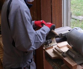 生徒が木材に電動やすりをかけている様子