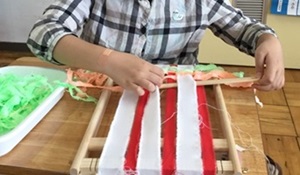 生徒が裂いた布を交互に通して織っている様子