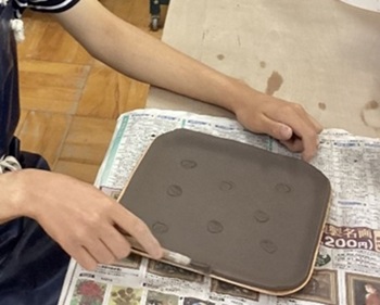 生徒が陶器の土を皿の形に成形している様子