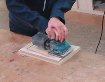 生徒が木材にやすりをかけている様子