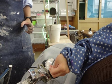 生徒が左手で機械のスイッチを押している様子