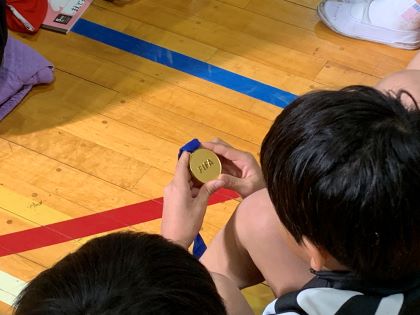 ワールドカップの金メダルを見つめる児童