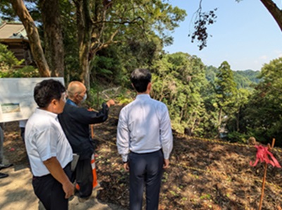 妙楽寺の森における現地視察の際、法面を見ながら町長の説明を聞く知事の画像