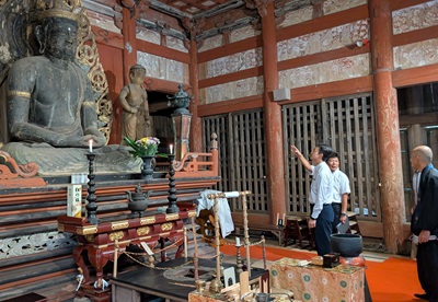 妙楽寺の森における現地視察の際、木造大日如来坐像を見ながら町長の説明を聞く知事の画像