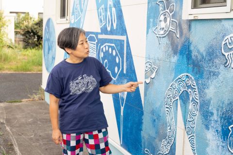 屋外の壁面に描かれた青い絵を紹介するこまちださんの写真です。