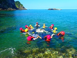 子dもたちが海で手をつないで浮かび、楽しむ写真