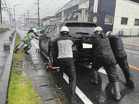複数の作業員が放置車両を移動させている様子1