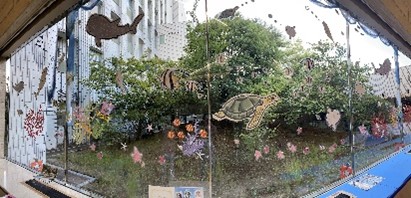 病院の窓ガラスに小さく多彩なビーズで形作られた魚や亀の水中をイメージしたガラスアート写真