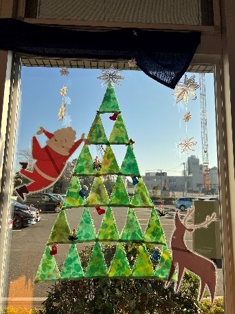 病院の窓ガラスに小さく多彩なビーズで形作られたサンタやトナカイ、クリスマス ツリーのガラスアート写真