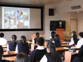 生徒がスクリーンに映されたスライド資料を見ている。