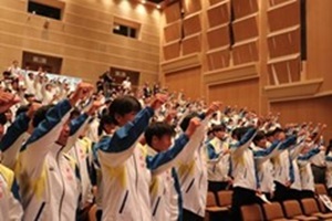 手を挙げて勝どきを行う監督・選手団の写真