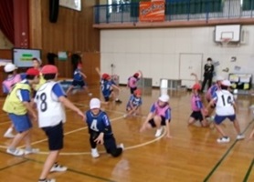 体育館で体を動かしている児童たちの写真