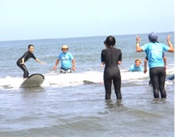 海でサーフィンボードの扱い方を習う児童たちの写真