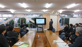 パワーポイントで発表する生徒と、視察する委員たちの写真