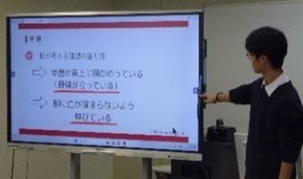モニターを指さしながら説明する生徒1名の写真