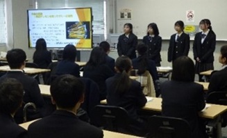モニターの前で説明する生徒4名と、発表を聞く生徒たちの写真